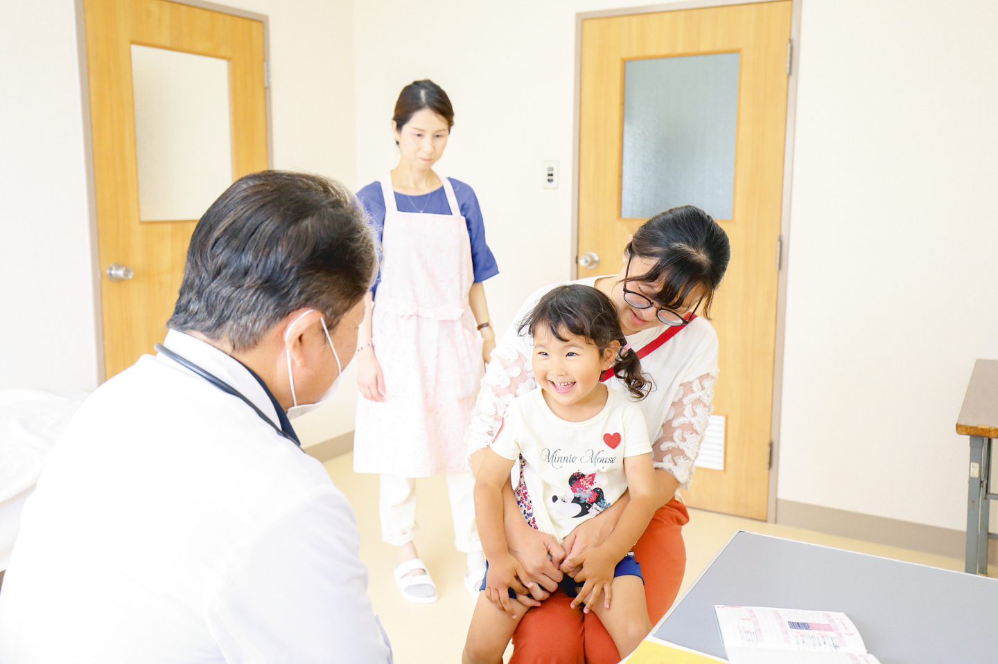 子どもが笑顔でお医者さんの健診を受けている写真