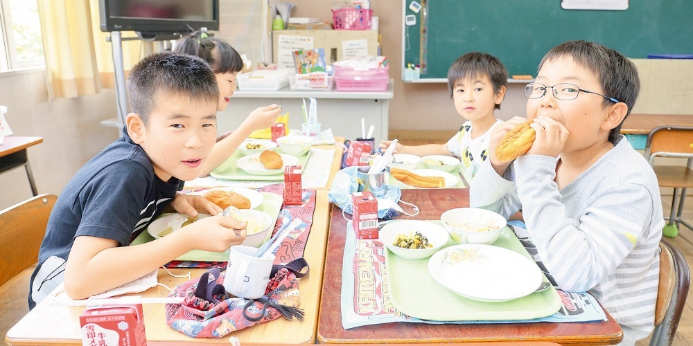 給食を楽しむ四人の小学生の写真